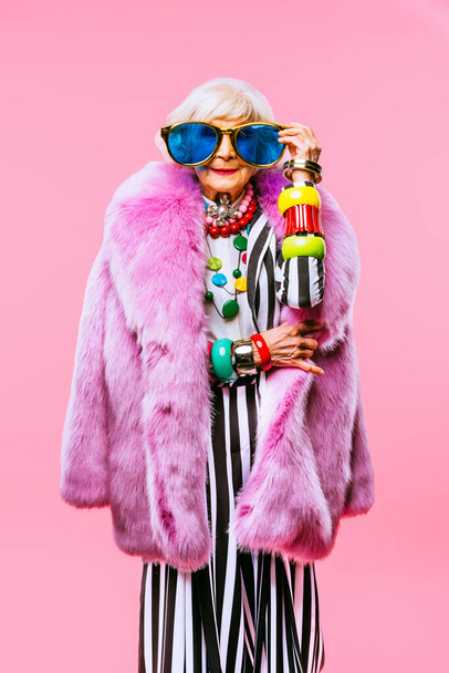 Happy and funny cool old lady with fashionable clothes portrait on colored background - Youthful grandmother with extravagant style, concepts about lifestyle, seniority and elderly people - Foto, afbeelding