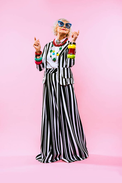 Happy and funny cool old lady with fashionable clothes portrait on colored background - Youthful grandmother with extravagant style, concepts about lifestyle, seniority and elderly people - Foto, Bild