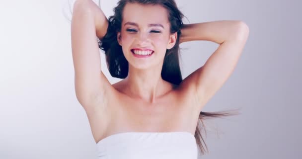 Her beauty is fully achieved with a smile. 4k video footage of a beautiful young woman playing with her hair in the studio. - Video
