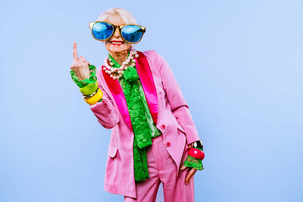 Happy and funny cool old lady with fashionable clothes portrait on colored background - Youthful grandmother with extravagant style, concepts about lifestyle, seniority and elderly people - Photo, image