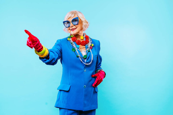 Happy and funny cool old lady with fashionable clothes portrait on colored background - Youthful grandmother with extravagant style, concepts about lifestyle, seniority and elderly people - 写真・画像