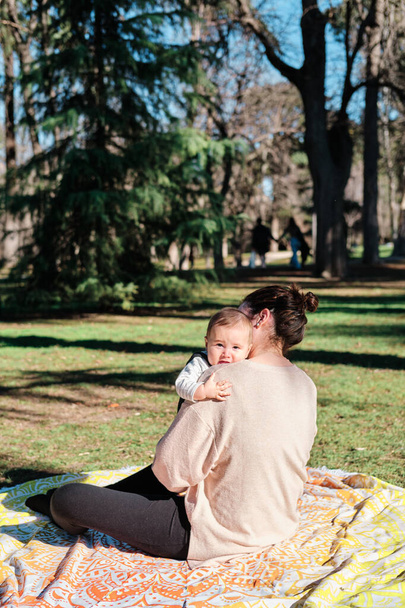 晴れた日に公園で赤ちゃんと遊んでいる若い女性 - 写真・画像