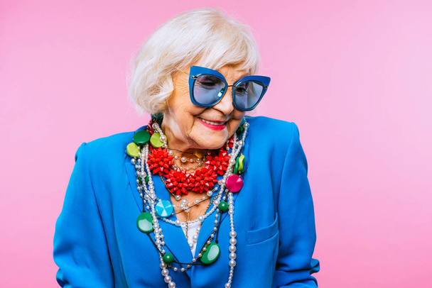 Happy and funny cool old lady with fashionable clothes portrait on colored background - Youthful grandmother with extravagant style, concepts about lifestyle, seniority and elderly people - Фото, изображение