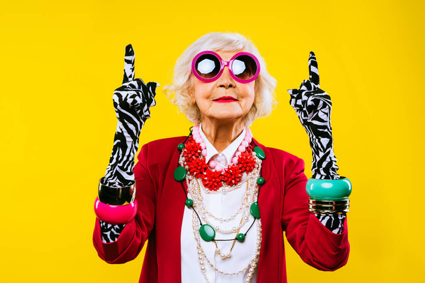 Happy and funny cool old lady with fashionable clothes portrait on colored background - Youthful grandmother with extravagant style, concepts about lifestyle, seniority and elderly people - Photo, image