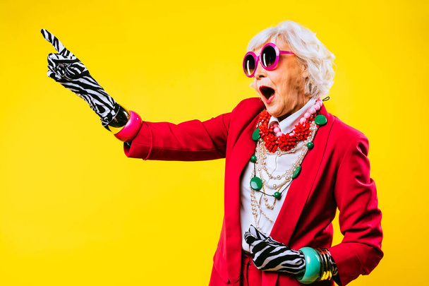 Happy and funny cool old lady with fashionable clothes portrait on colored background - Youthful grandmother with extravagant style, concepts about lifestyle, seniority and elderly people - Foto, immagini