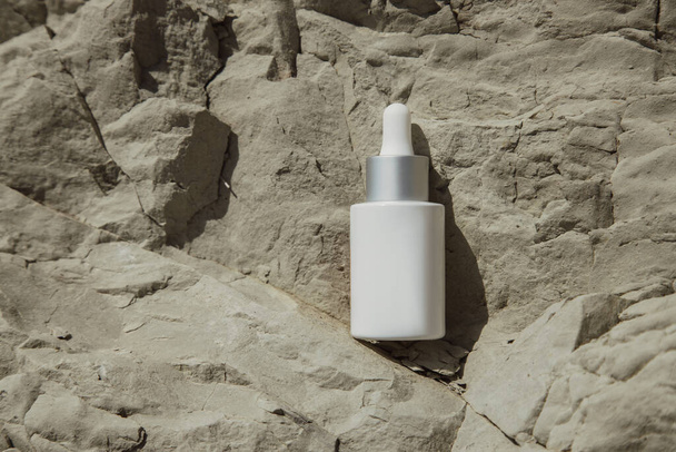 White bottle with a pipette on a stone background.Cosmetic bottle with pipette standing on the stone.White glass bottle - 写真・画像