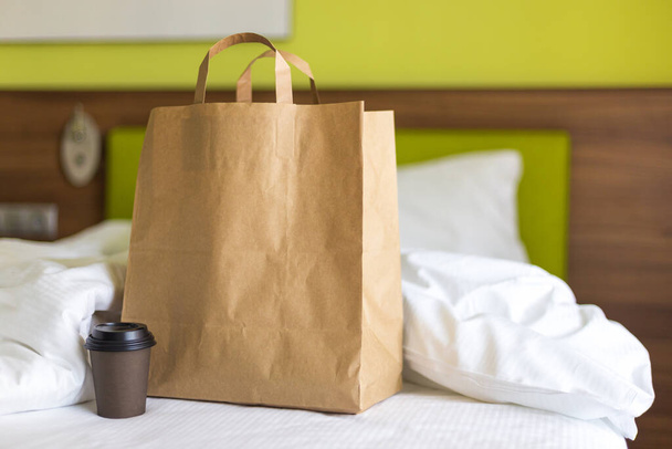 Lieferung Lebensmittel Craft Bag mit Tasse auf dem Bett an sonnigen Tag. Lieferung bei jedem Wetter rund um die Uhr an den Kunden. Fast Food Öko-Verpackung mit großem Frühstücksset - Foto, Bild