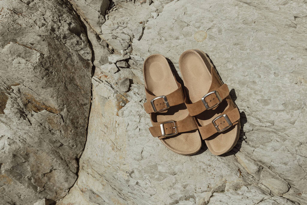 Pair of sandals on rocks.A pair of brown sandals on the rocks during the day. - Fotó, kép