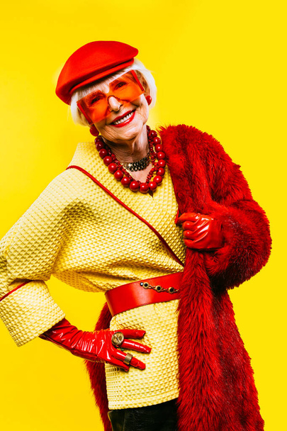 Happy and funny cool old lady with fashionable clothes portrait on colored background - Youthful grandmother with extravagant style, concepts about lifestyle, seniority and elderly people - Fotó, kép