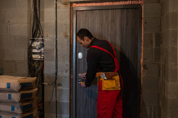 Male handyman carpenter at interior wood door lock installation - Foto, imagen