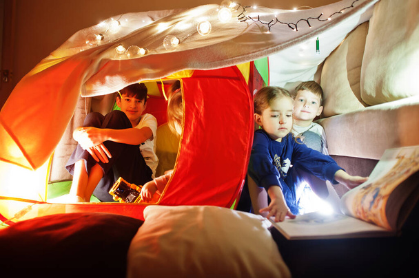 Playing kids in tent at night home. Hygge mood.  - Photo, image