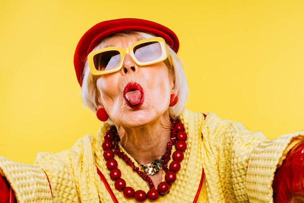 Happy and funny cool old lady with fashionable clothes portrait on colored background - Youthful grandmother with extravagant style, concepts about lifestyle, seniority and elderly people - Zdjęcie, obraz
