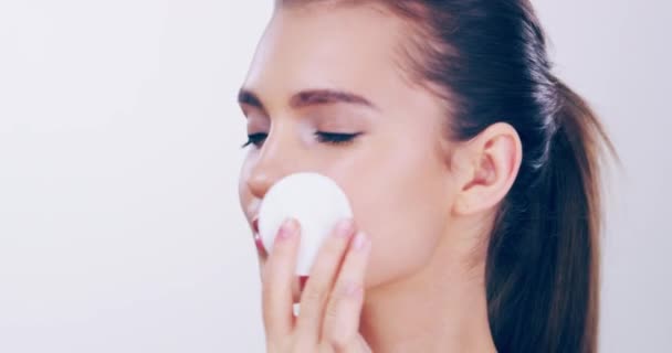 With great skin comes a great beauty regime. 4k video footage of a beautiful young woman wiping her face with a cotton pad in the studio. - Záběry, video