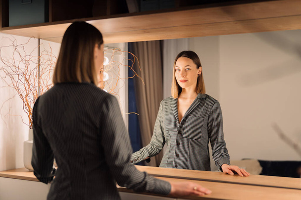 Krásná žena se dívá na svůj odraz v zrcadle - Fotografie, Obrázek
