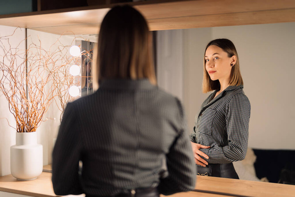 Urocza kobieta patrząc na swoje odbicie w lustrze - Zdjęcie, obraz