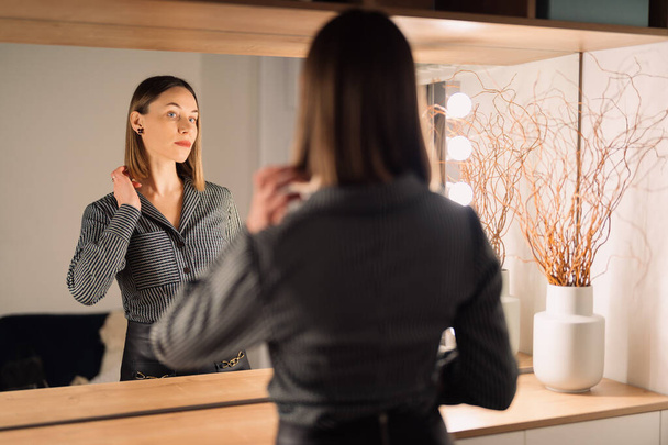 Υπέροχη γυναίκα που κοιτάζει την αντανάκλασή της στον καθρέφτη. - Φωτογραφία, εικόνα