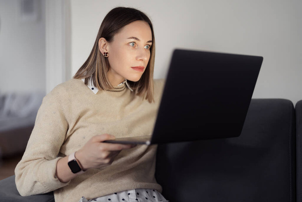 Kobieta gapi się na laptopa w domu w salonie - Zdjęcie, obraz