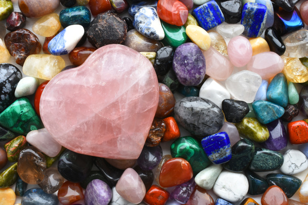 Ein Bild von oben mit einer Vielzahl von Heilkristallen mit einem großen Rosenquarzkristall-Herz.  - Foto, Bild