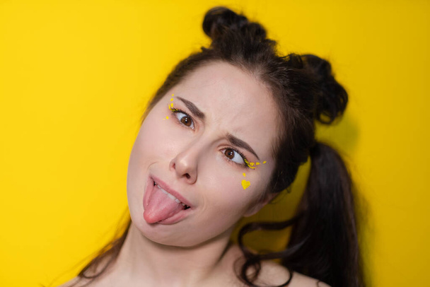 portrait of attractive brunette woman with little heart on face on yellow background. portrait of beautiful girl on colorful background - Φωτογραφία, εικόνα