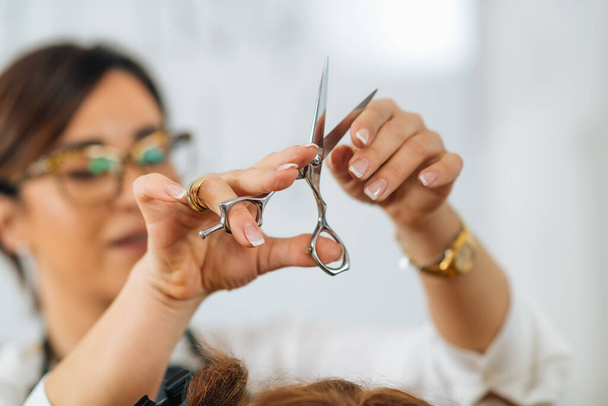 Hands of a hairdresser holding hairdressing scissors, explaining students haircutting techniques to students - Φωτογραφία, εικόνα