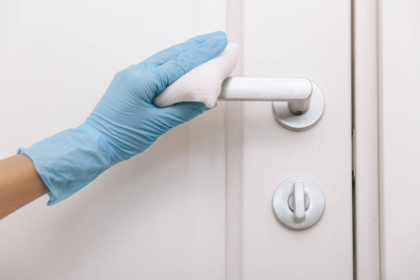 Cleaning black door handles with an antiseptic white wet wipe and sanitizer spray. Sanitize surfaces prevention in hospital and public spaces against corona virus. Woman hand using towel for cleaning - Photo, image