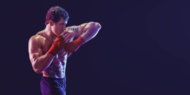 Vista lateral do kickboxer muscular que entrega cotovelo atingido isolado no fundo preto. Meios mistos - Foto, Imagem