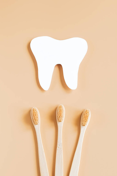 Día Internacional del Dentista. Feliz día de los dentistas. Cepillos de dientes de madera ecológicos sobre fondo beige de moda. Concepto de cuidado dental. Tarjeta de felicitación. - Foto, Imagen