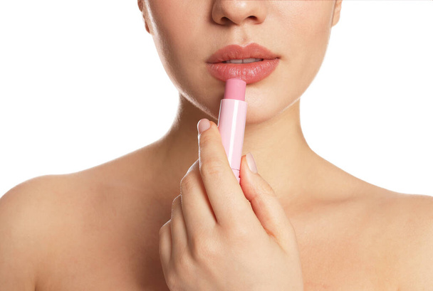 Young woman applying lip balm on white background, closeup - Photo, image