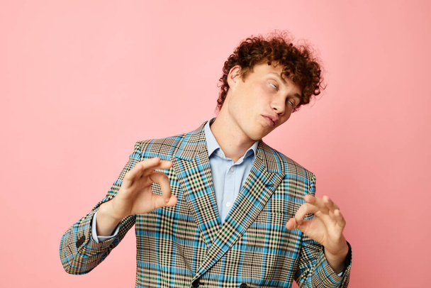 Young curly-haired man gesturing with his hands emotions checkered jacket pink background unaltered - Photo, image
