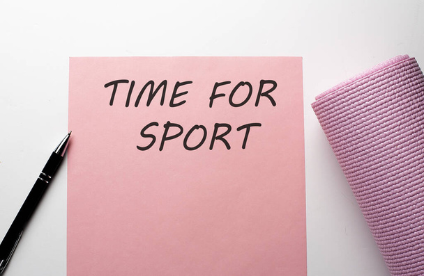 Ροζ στρώμα γυμναστηρίου και ροζ χαρτί με κείμενο TIME FOR SPORT σε λευκό φόντο . - Φωτογραφία, εικόνα