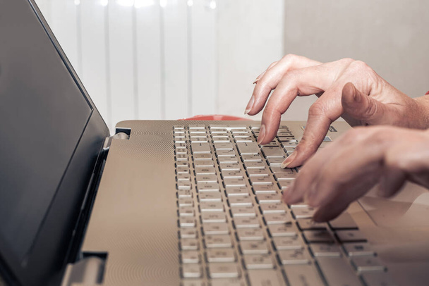 Female hands on laptop keyboard at home. Homeschooling and remote work. - Foto, Imagem