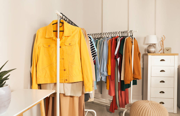 Racks with stylish clothes in cozy room interior. Fast fashion - Foto, imagen