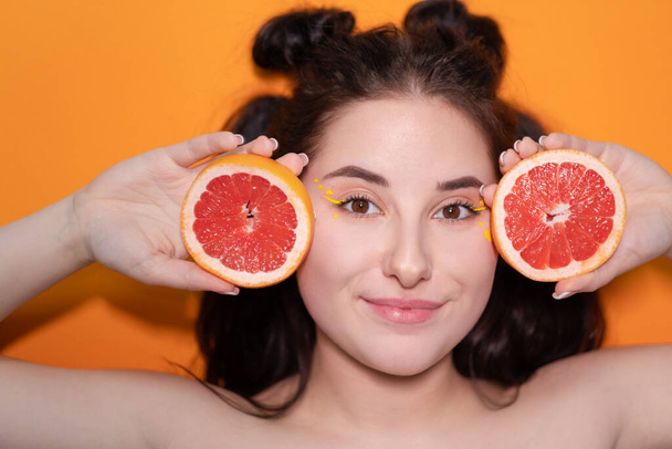 jeune femme fille avec tranche de pamplemousse sur fond orange - Photo, image