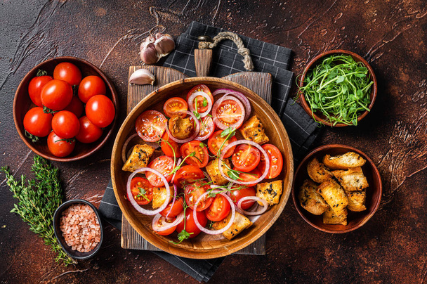 Ensalada toscana de Panzanella, ensalada clásica vegetariana con tomates, cebolla y croutons. Fondo oscuro. Vista superior - Foto, imagen