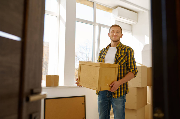 Молодий чоловік несе картонну коробку під час переїзду
 - Фото, зображення