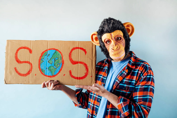 Человек в обезьяньей маске показывает знак "S.O.S".. - Фото, изображение
