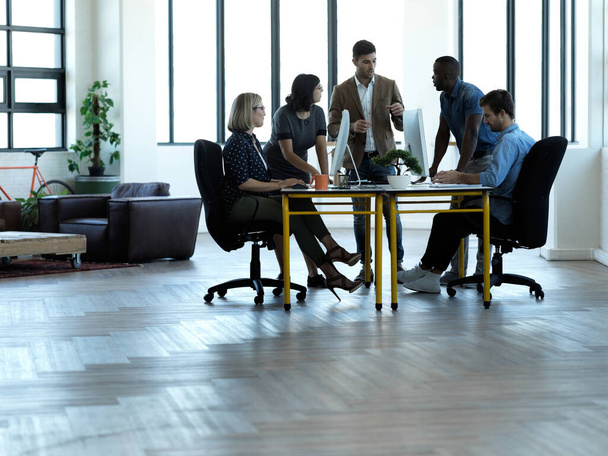 オフィスのテーブルの周りに集まったビジネスマンのグループの完全な長さのショット - 写真・画像