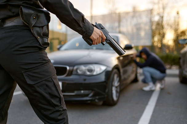 Kadın polis araba hırsızının özgeçmişine silah doğrultuyor. - Fotoğraf, Görsel