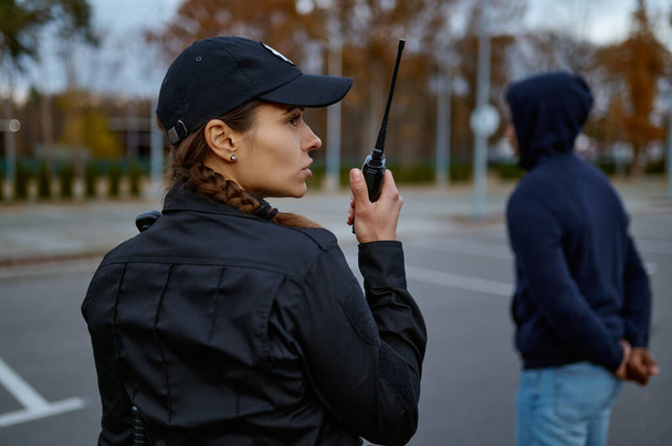 Woman cop using portable radio back view - 写真・画像