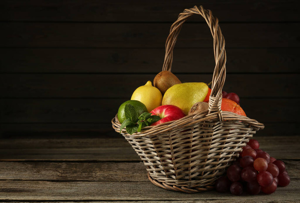 Fresh ripe fruits in wicker basket on wooden table, space for text - Fotografie, Obrázek