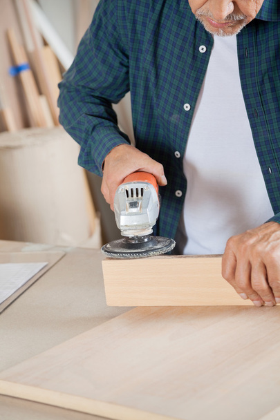 Senior Carpenter Using Electric Sander On Wood - Photo, Image