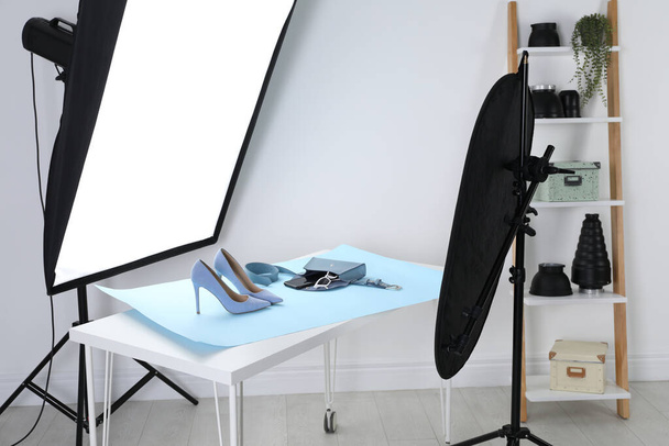 Professional lighting equipment near table with fashionable women's shoes and accessories in photo studio - Foto, imagen