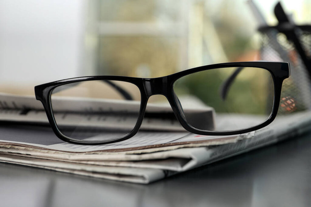 Stack of newspapers and glasses on grey table indoors, closeup - Фото, зображення