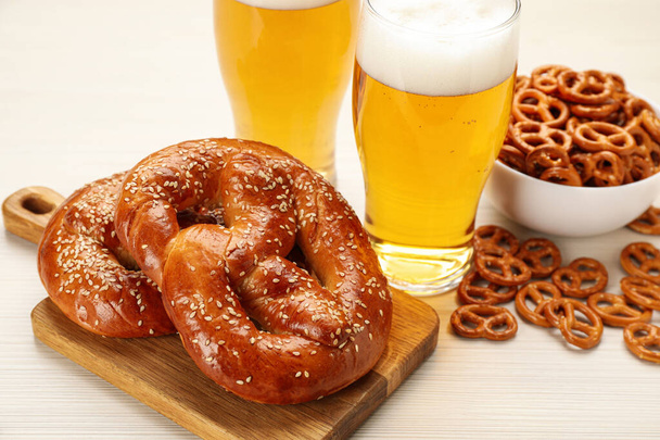 Tasty pretzels, crackers and glasses of beer on white wooden table - Foto, Bild