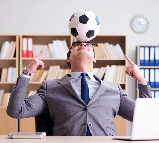 Бізнесмен з футбольним м'ячем в офісі
 - Фото, зображення