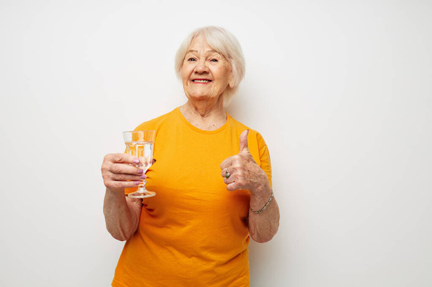 Photo of retired old lady in casual t-shirt glasses glass of water cropped view - Fotó, kép
