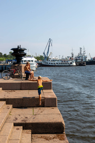 Petrohrad, Rusko - 16. července 2021: Děti se koupají na molu Petrovskaya v Kranstadtu na břehu Finského zálivu - Fotografie, Obrázek