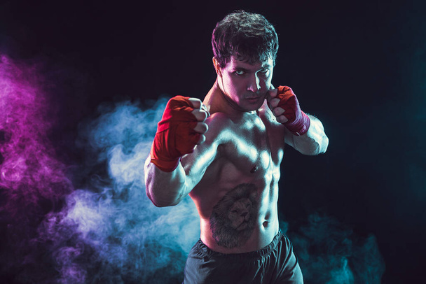 Studio shot of shirtless boxer fighter who preparing for fight on smoke background. Sport concept - Φωτογραφία, εικόνα
