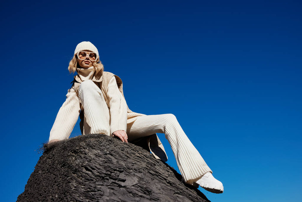τουρίστας κάθεται σε μια πέτρα φύση μπλε ουρανό σε ένα τοπίο καπέλο - Φωτογραφία, εικόνα