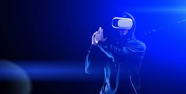 Vr goggles virtual reality. Young man in digital helmet for 3d virtual reality game on dark background. Study and virtual world in 3D simulation - Foto, afbeelding